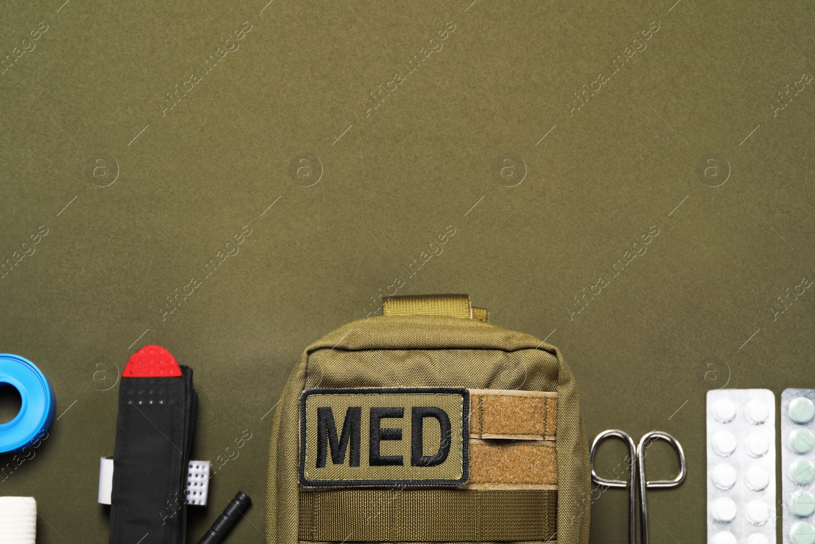 Photo of Flat lay composition with military first aid kit on khaki background. Space for text