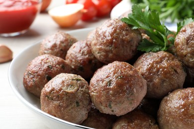 Photo of Tasty cooked meatballs and parsley on table, closeup view
