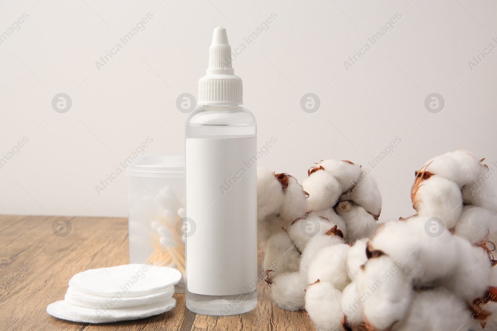 Photo of Composition with makeup remover and cotton flowers on wooden table against white background
