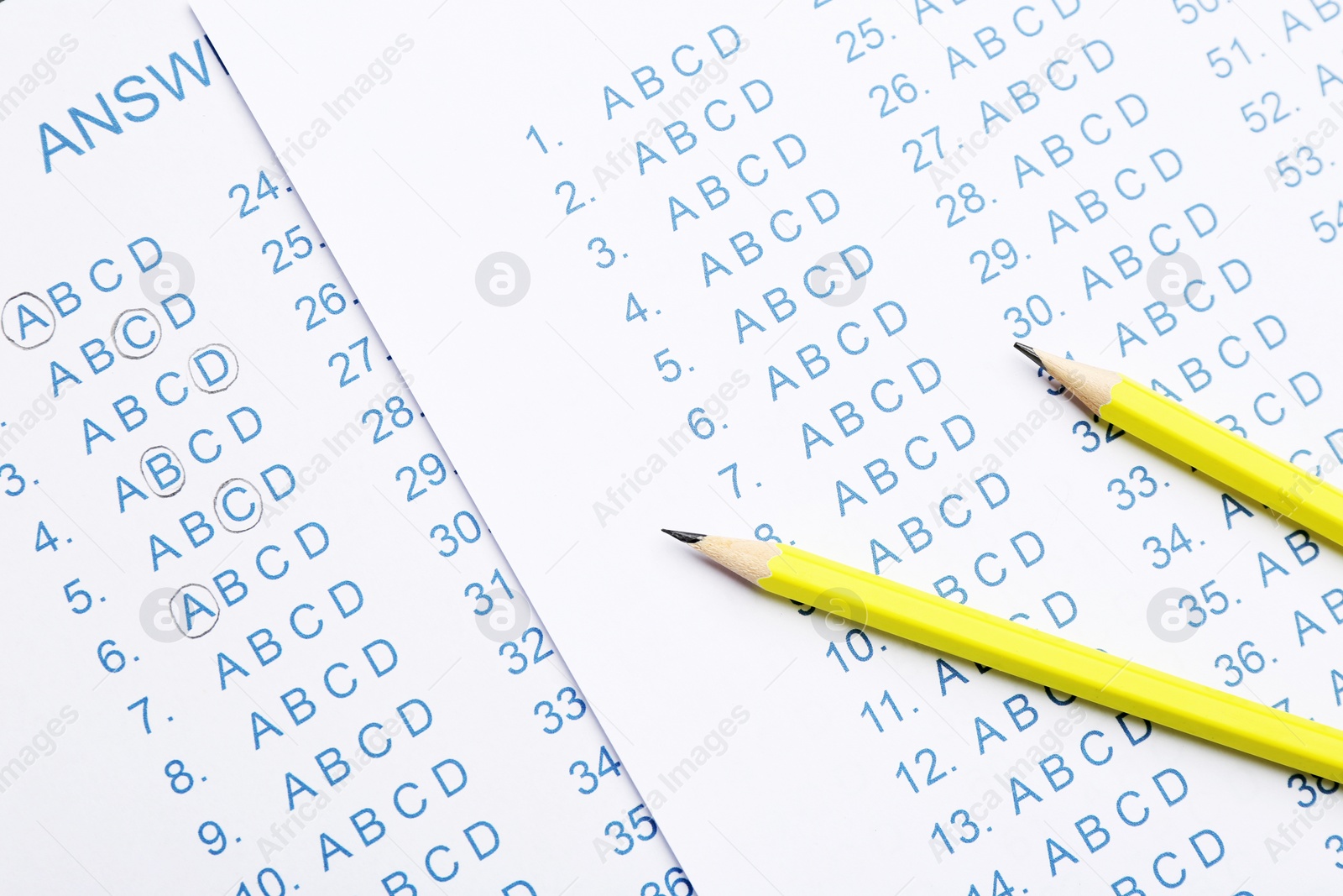 Photo of Yellow pencils on answer sheets, top view