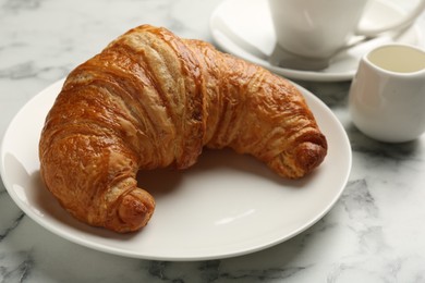 Photo of Delicious fresh croissant on light marble table, closeup