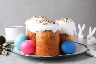 Photo of Traditional Easter cakes and painted eggs on light grey table