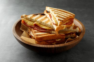 Photo of Tasty sandwiches with ham and melted cheese in bowl on grey table, closeup