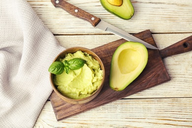 Flat lay composition with guacamole and ripe avocado on wooden background
