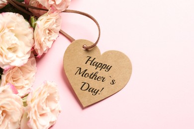 Image of Happy Mother's Day. Heart shaped greeting label and beautiful flowers on pink background