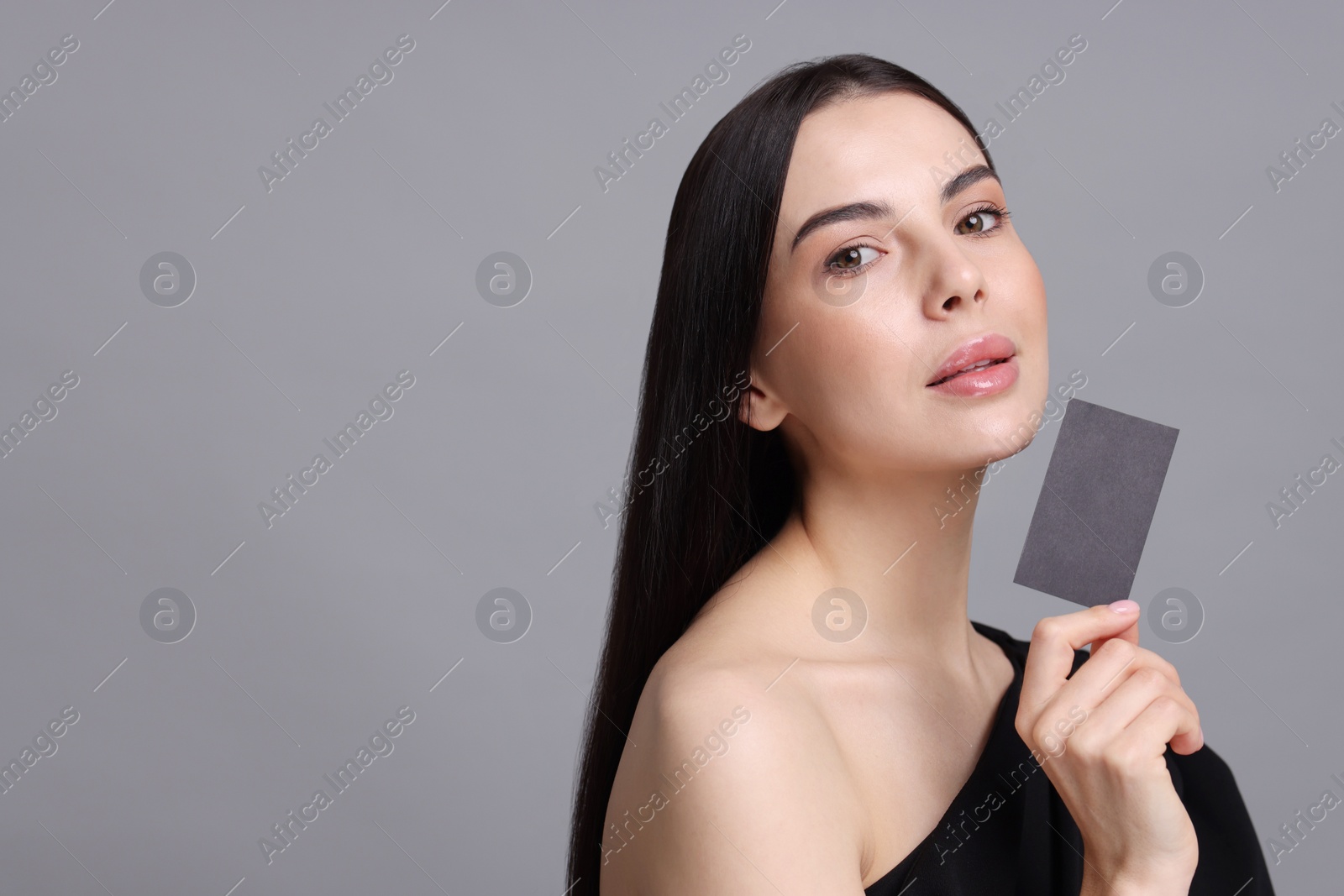 Photo of Woman holding blank business card on grey background. Space for text