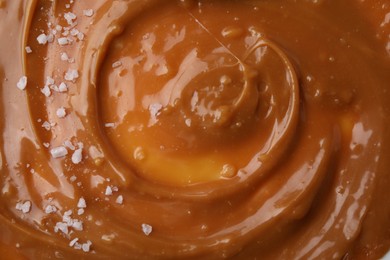 Photo of Delicious caramel sauce with sea salt as background, closeup