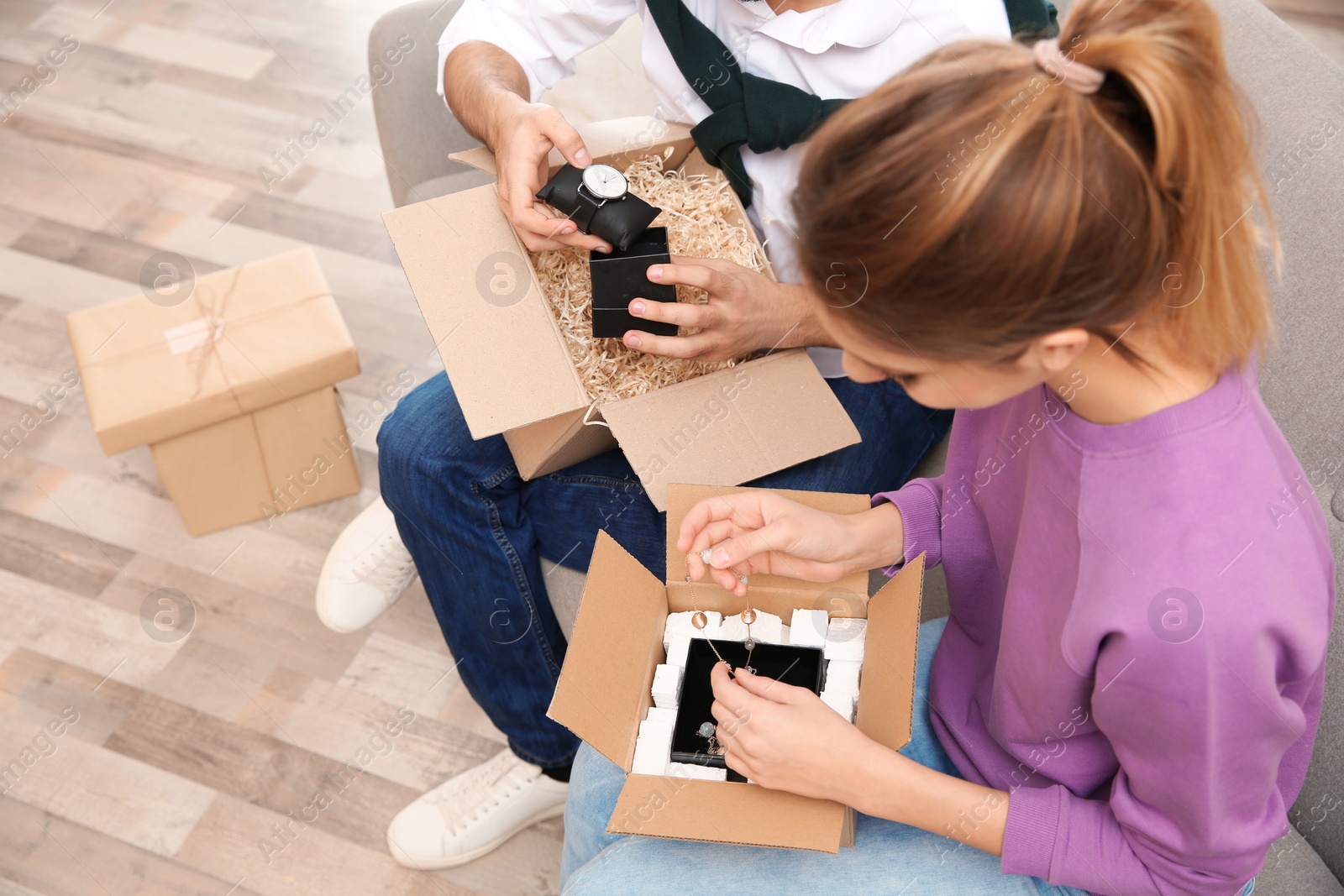 Photo of Young couple opening parcels in living room, closeup