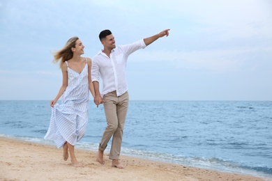 Happy couple having romantic walk on beach. Space for text