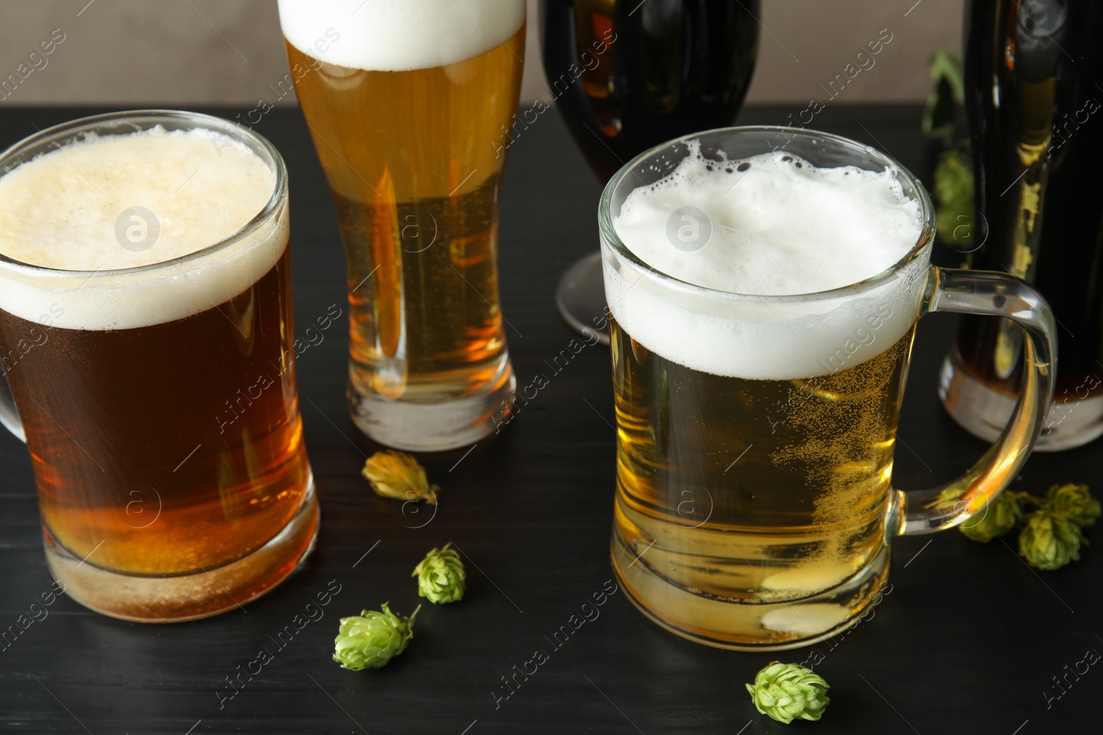 Photo of Composition with tasty beers and fresh green hops on table