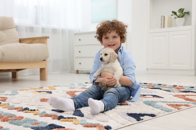 Photo of Little boy with cute puppy on carpet at home