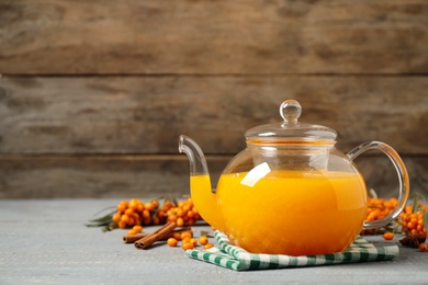 Photo of Delicious sea buckthorn tea, fresh berries and spices on grey wooden table. Space for text