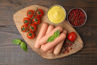 Photo of Delicious boiled sausages, sauce, tomatoes and spices on wooden table, flat lay