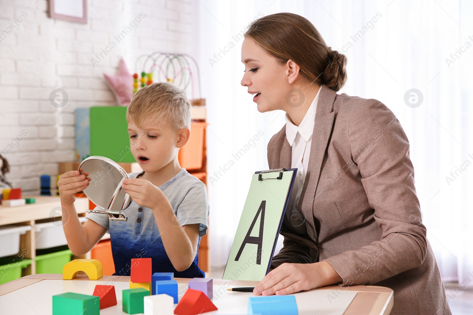 Photo of Speech therapist working with little boy in office