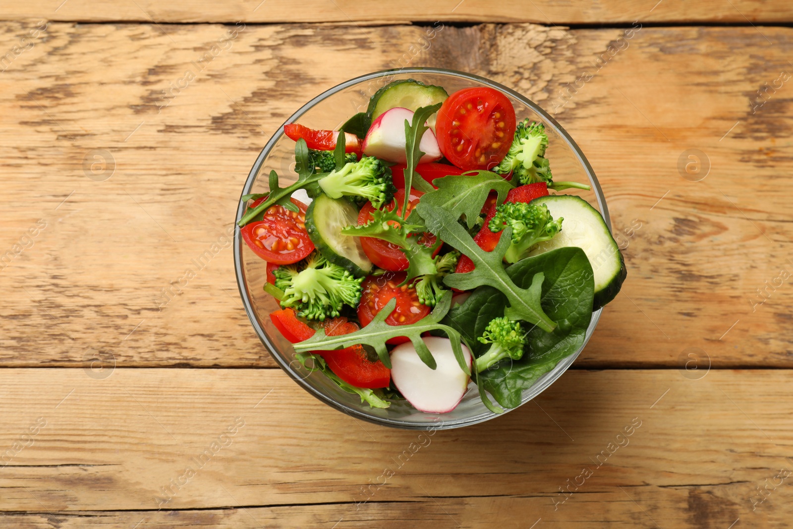 Photo of Tasty fresh vegetarian salad on wooden table, top view