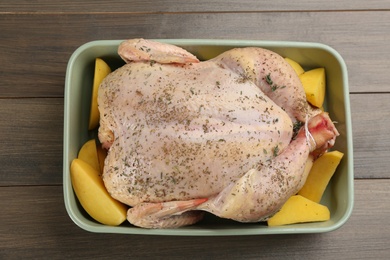 Raw chicken with potatoes and thyme on wooden table, top view