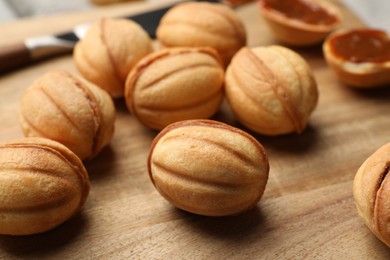 Photo of Homemade walnut shaped cookies with boiled condensed milk on wooden board, closeup
