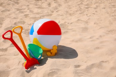 Photo of Different beach toys and inflatable ball on sand outdoors, space for text