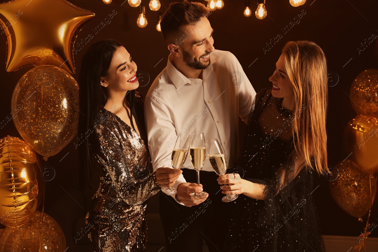 Photo of Happy friends with glasses of sparkling wine celebrating New Year indoors