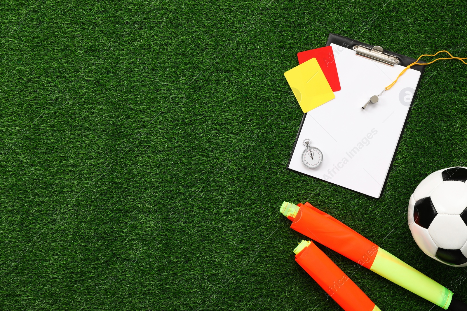 Photo of Soccer ball and different referee equipment on green grass, flat lay. Space for text
