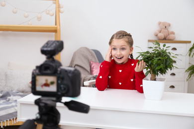 Photo of Emotional little blogger with plant recording video at home