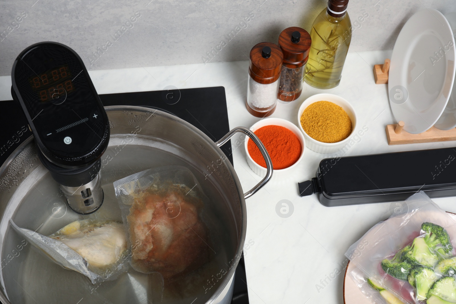 Photo of Thermal immersion circulator and vacuum packed meat in pot on table. Sous vide cooking