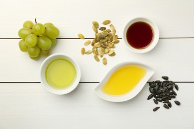 Photo of Vegetable fats. Different cooking oils in bowls and ingredients on white wooden table, flat lay