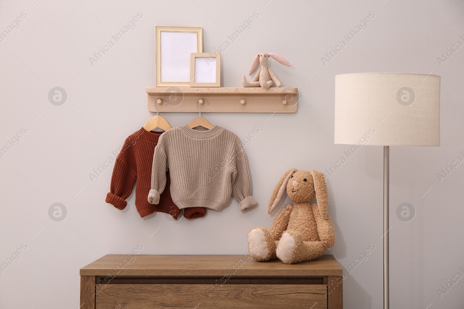 Photo of Children's room interior with stylish wooden furniture, baby clothes and lamp