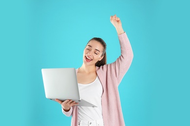 Photo of Portrait of happy young woman in casual outfit with laptop on color background