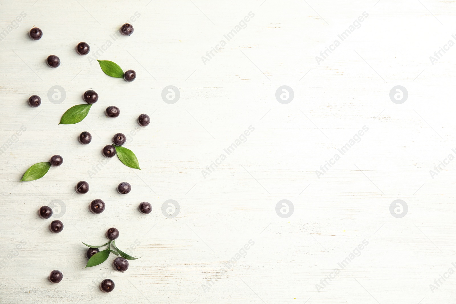 Photo of Flat lay composition with fresh acai berries and leaves on wooden background