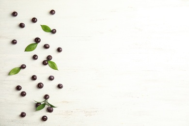 Flat lay composition with fresh acai berries and leaves on wooden background