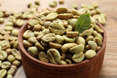 Green coffee beans and leaf on wooden table, closeup