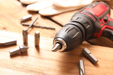 Electric screwdriver with bit set on wooden table, closeup