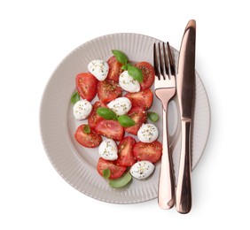 Plate of tasty salad Caprese with mozarella balls, tomatoes, basil and cutlery on white background, top view