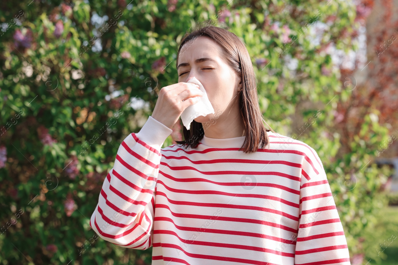 Photo of Woman with napkin suffering from seasonal allergy outdoors