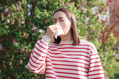 Photo of Woman with napkin suffering from seasonal allergy outdoors