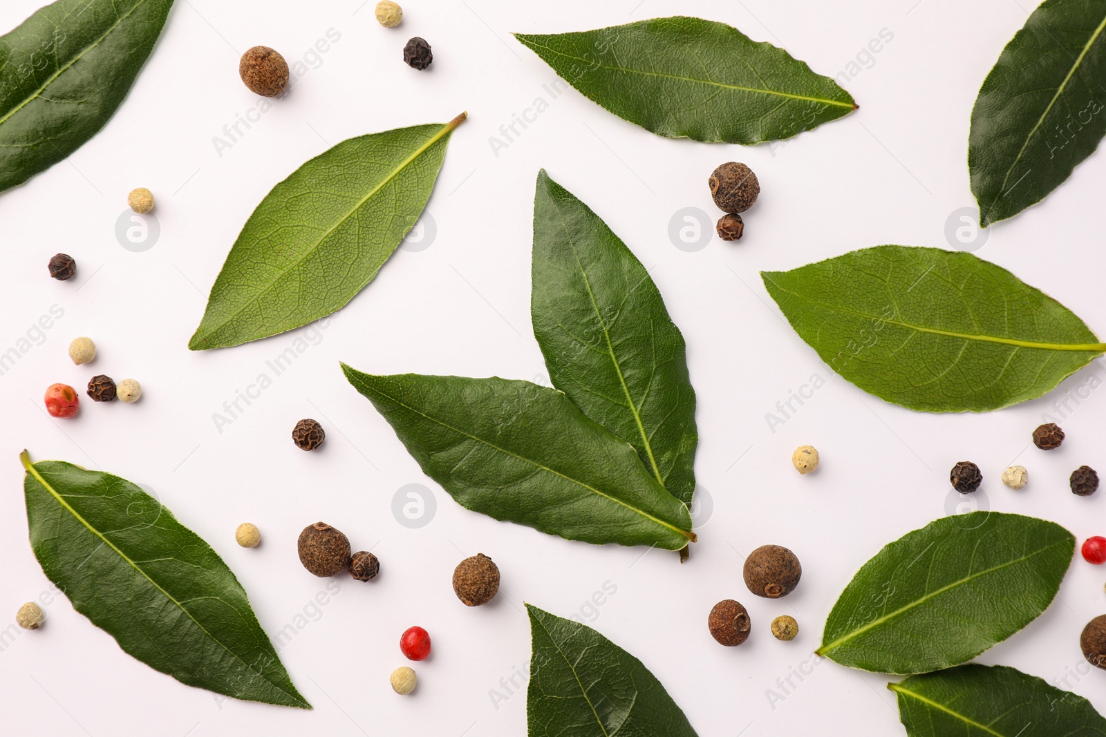 Photo of Aromatic bay leaves and spices on white background, flat lay