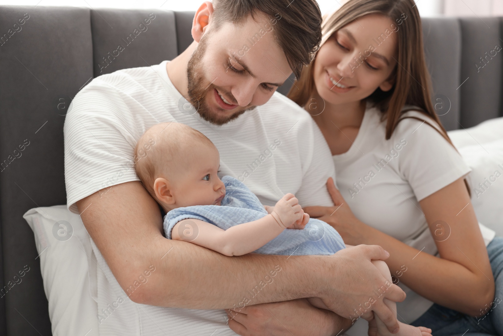 Photo of Happy family. Parents with their cute baby on bed indoors