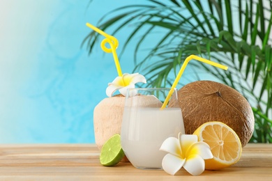 Photo of Composition with glass of coconut water on wooden table against blue background. Space for text
