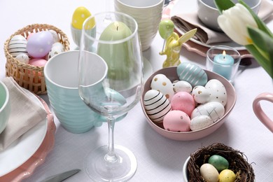 Photo of Festive table setting with painted eggs, closeup. Easter celebration