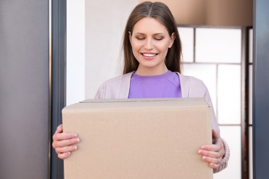 Photo of Portrait of smiling woman with parcel at door, mockup for design. Delivery service