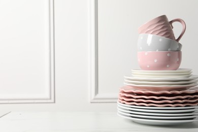 Photo of Beautiful ceramic dishware and cup on white marble table, space for text