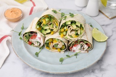Photo of Delicious sandwich wraps with fresh vegetables and slice of lime on white marble table