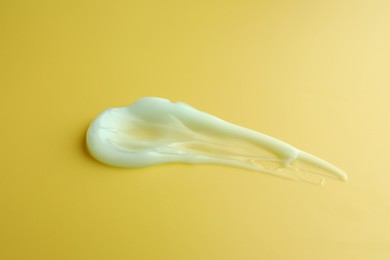 Photo of Sample of face cream on yellow background, top view