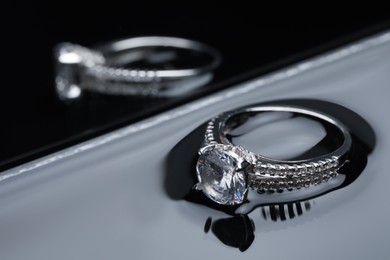 Photo of Luxury jewelry. Elegant ring on dark mirror surface, closeup
