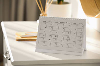 Photo of Paper calendar on white chest of drawers indoors