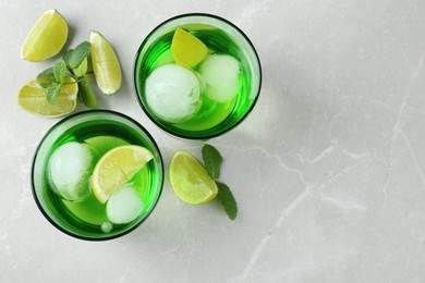 Photo of Delicious cocktails with lime and ice balls on grey table, flat lay, Space for text