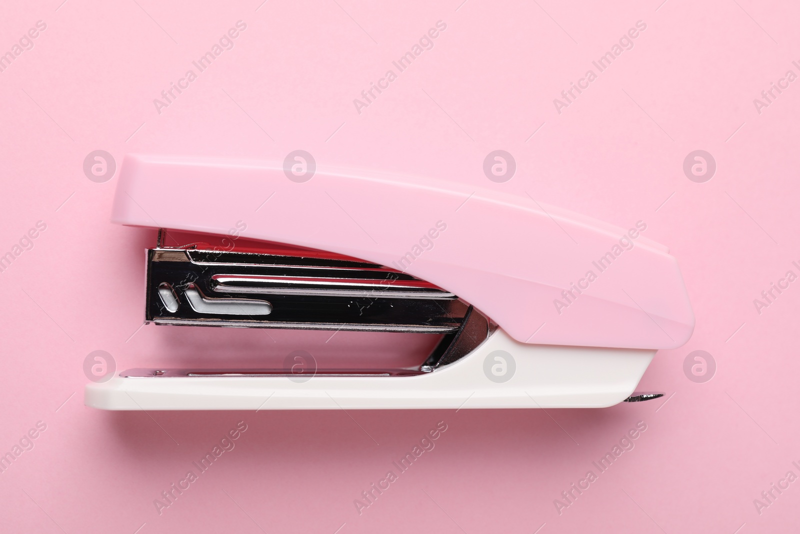 Photo of One new stapler on pink background, top view