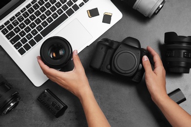 Photo of Woman with professional photographer equipment and laptop at gray table