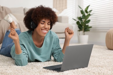Photo of Beautiful young woman in headphones using laptop in room